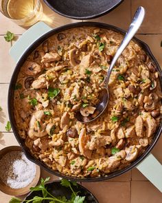 a skillet filled with chicken and rice on top of a table