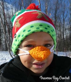 a young boy wearing a knitted hat with a fake nose and nose piece in the shape of a duck