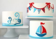 two cakes decorated with sailboats and buntings on top of each cake stand