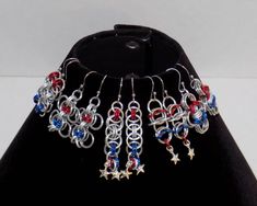 a pair of earrings with red, white and blue beads hanging from it's holder