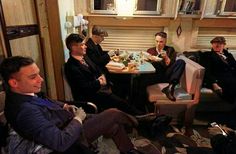 a group of men sitting around a table with food and drinks on top of it