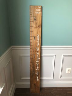 a tall wooden ruler with the word family on it in front of a blue wall