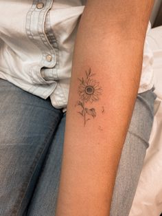 a woman's arm with a tattoo on it that has a sunflower in the middle