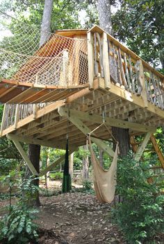 a wooden tree house with hammock hanging from it's roof