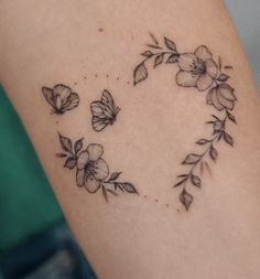 a heart shaped tattoo with flowers and butterflies on it's left side ribcage