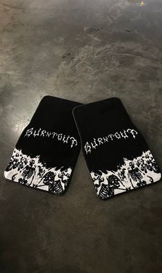 two black and white skateboards laying on top of a cement floor next to each other