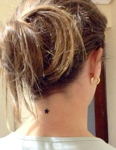 the back of a woman's head with a small star tattoo on her neck