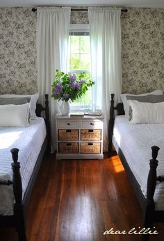 two twin beds in a bedroom with floral wallpaper on the walls and wooden floors