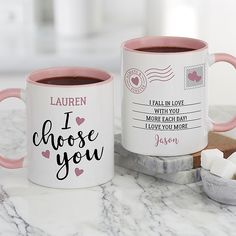 two coffee mugs with i choose you written on them next to marshmallows