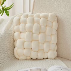 a white pillow sitting on top of a couch next to a book