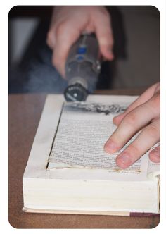 a person is using a bottle to open an old book