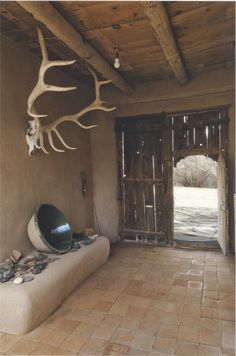 an antler's head hangs from the ceiling in a room with stone flooring