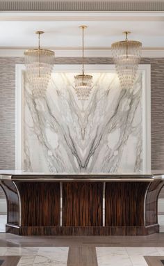 an elegant marble and wood lobby with chandelier above the reception table in front of a large painting