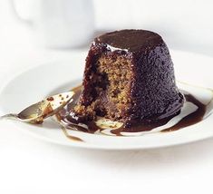 a piece of chocolate cake on a white plate with caramel syrup drizzled around it