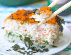 two chopsticks sticking out of a layered sushi dish on a white plate