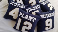 four pillow cases with white and blue football jerseys on them sitting on top of a bed