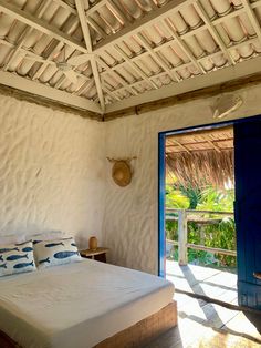 a bed in a room with a wooden ceiling and blue doors leading to the outside