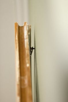 a close up of a door handle on a wooden frame with white walls in the background