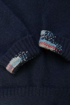 a close up of a blue sweater with a white and red design on the collar