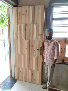 a man standing in front of a door made out of plywood planks with a turban on his head