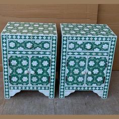 pair of green and white painted wooden nightstands with flowers on the doors, side by side