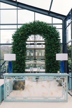 a table with two lamps and a large green wreath in the middle of it's room