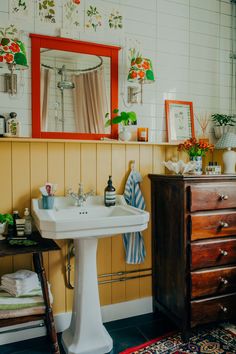 a white sink sitting under a bathroom mirror next to a wooden dresser with drawers on it