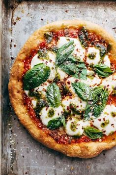 an uncooked pizza with basil, mozzarella and parmesan cheese