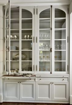 a large white china cabinet with glass doors