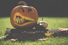 a carved pumpkin sitting on top of a log