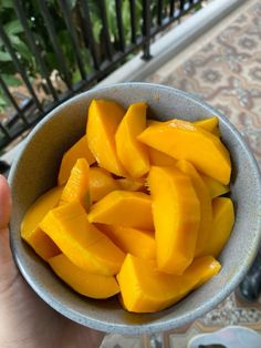 a person holding a bowl full of sliced mangoes