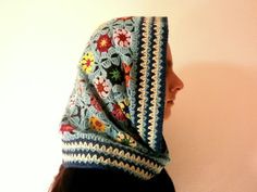 a woman wearing a crocheted head scarf with flowers on it's side