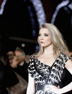 a woman with long red hair is walking down the runway wearing a black and white dress