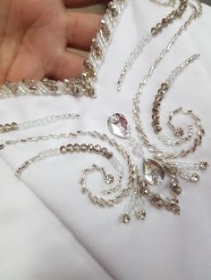 a person is holding onto a white cloth with silver chains and crystal beads on it