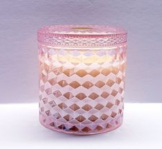 a pink glass candle holder sitting on top of a white table next to a wall