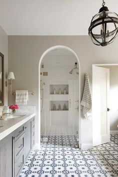 a bathroom with blue and white tile flooring next to a chandelier hanging from the ceiling