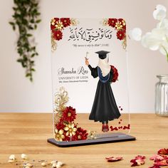 an acrylic plaque with a graduate's cap and gown on it, surrounded by flowers