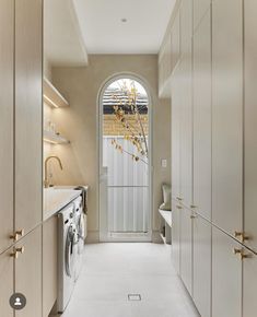 a long narrow hallway leading to a washer and dryer in a home kitchen