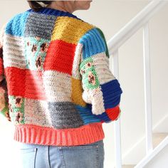 a woman wearing a multicolored sweater and jeans stands on the stairs with her hands in her pockets