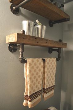 two towels hanging on the wall above a toilet in a bathroom with metal buckets