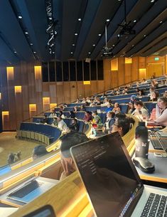 people are sitting in an auditorium with laptops