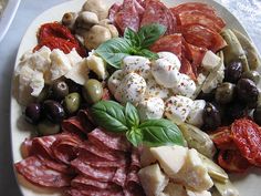 a white plate topped with lots of different types of meats and veggies