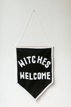 a black and white banner hanging on the wall with words witches welcome written across it