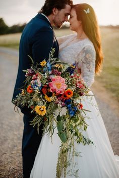 a bride and groom standing together in the middle of a road with flowers on their bouquet