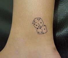 a small black and white dice tattoo on the ankle