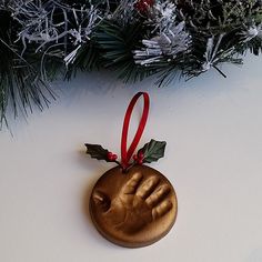 a wooden ornament with a hand and holly on it hanging from a christmas tree