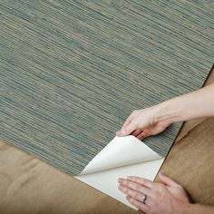 a person is wrapping up a piece of paper on top of a rug that's laying on the floor