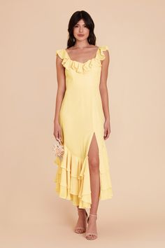 a woman is wearing a yellow dress with ruffles on the side and one leg