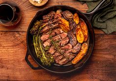 steak, potatoes and broccoli in a cast iron skillet on a wooden table