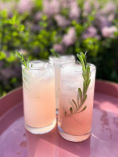 two glasses filled with drinks sitting on top of a pink tray